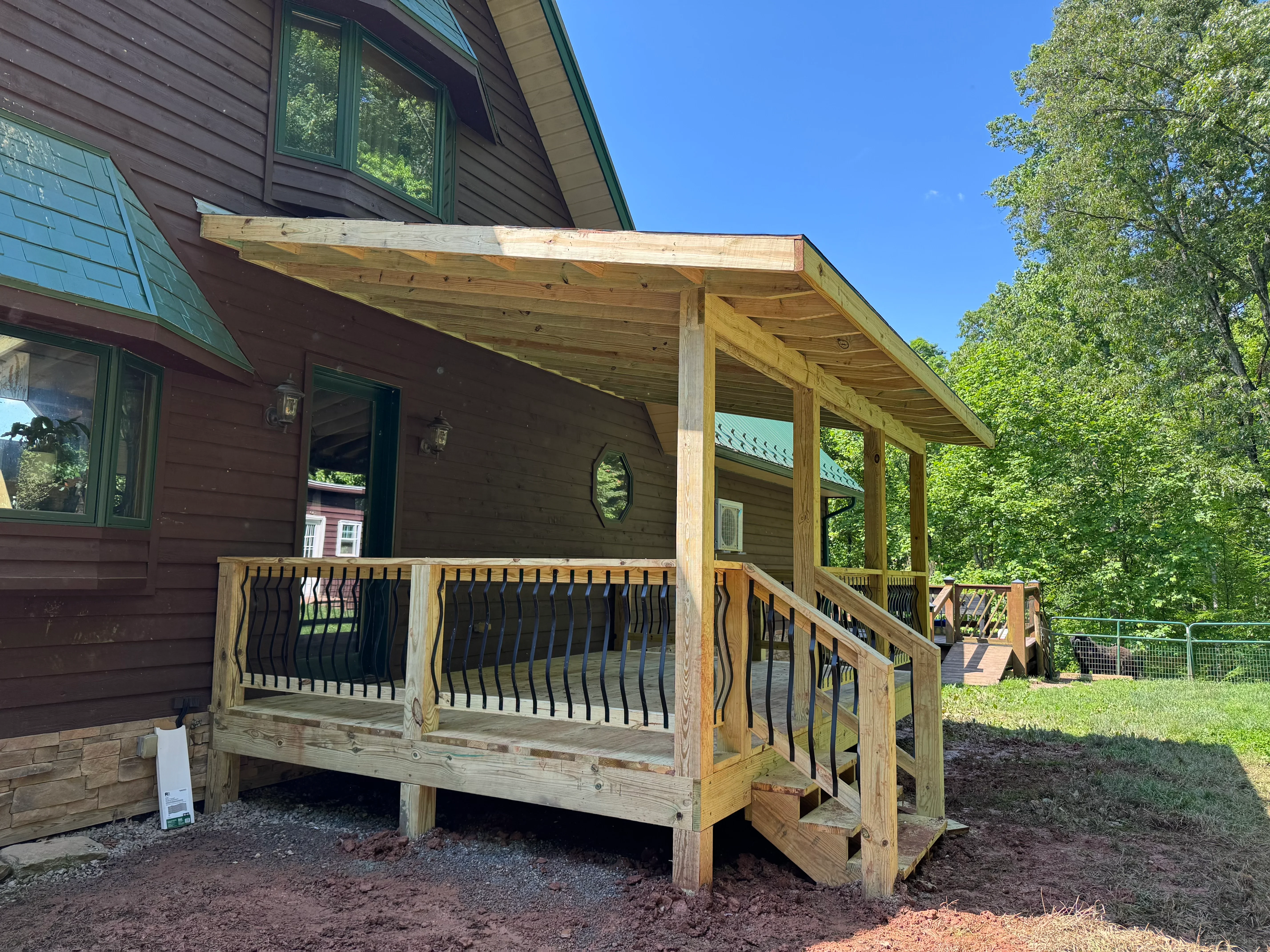 Wooden deck with pergola cover, metal railings, and timber framing attached to residential home