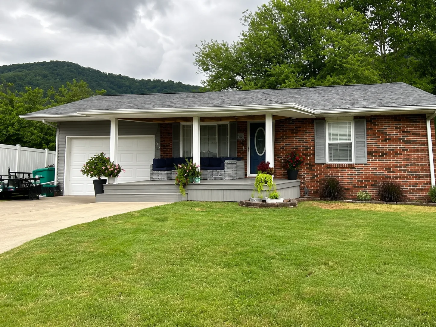 Gray architectural shingle roof on brick ranch home with white trim and front porch